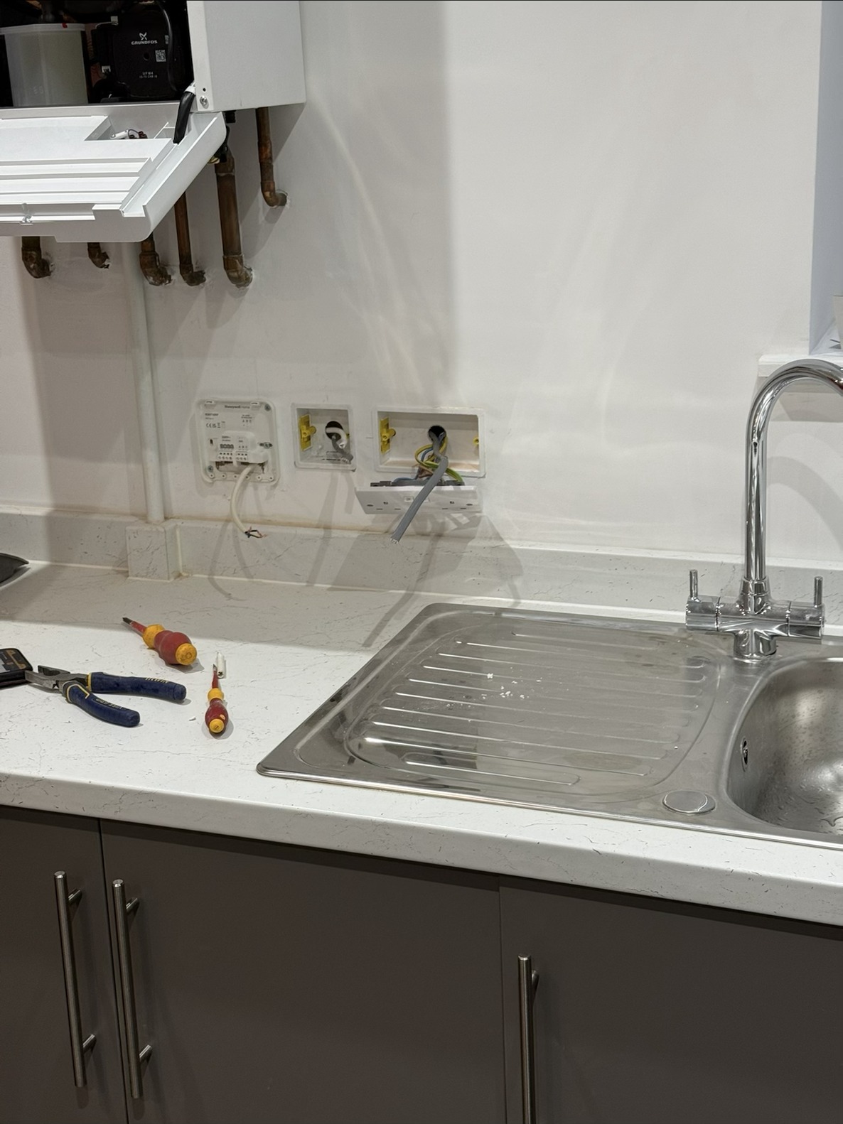 Plumbing and electrical repair work under a kitchen sink